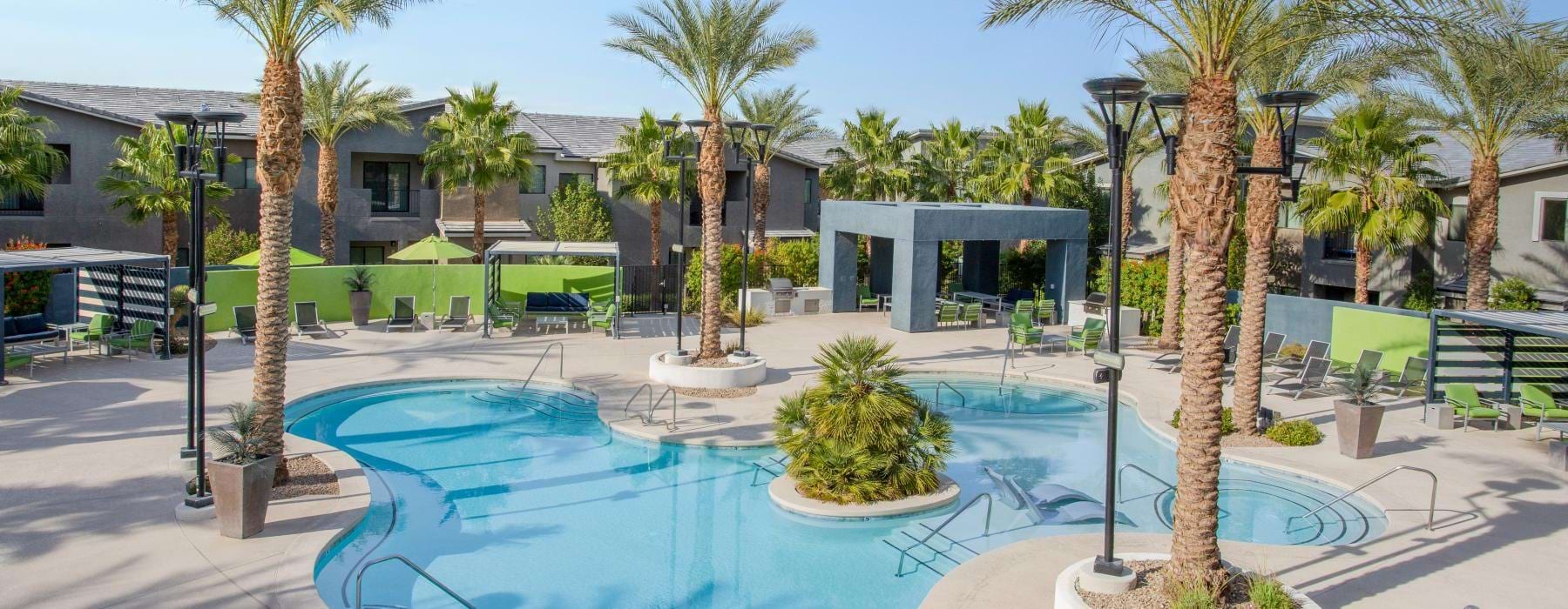 a pool with palm trees and buildings in the background